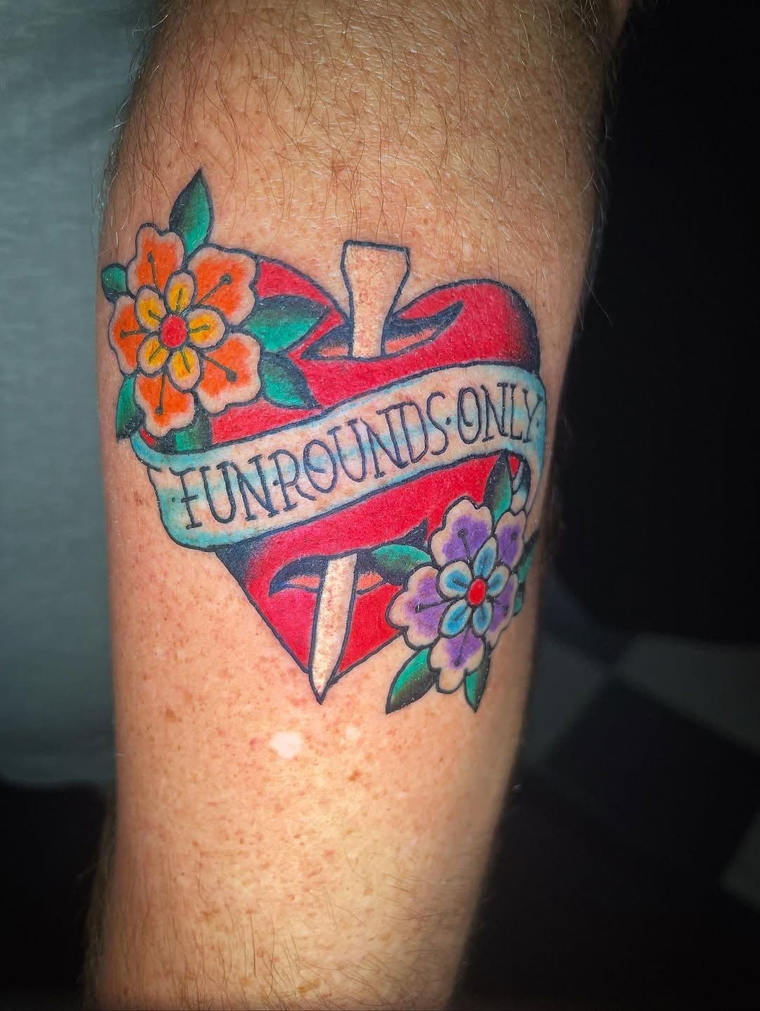 Colorful traditional heart and dagger tattoo with flowers on forearm