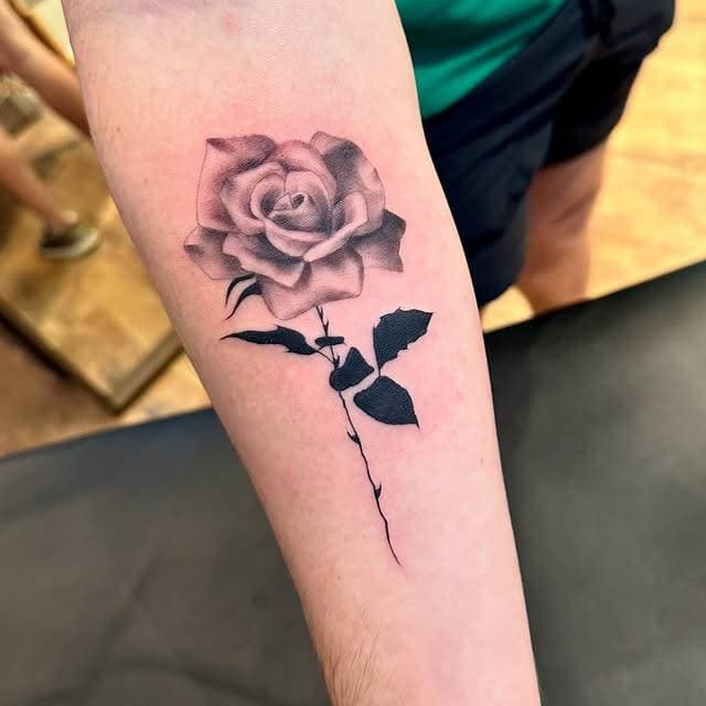 Black and grey realistic rose tattoo on forearm
