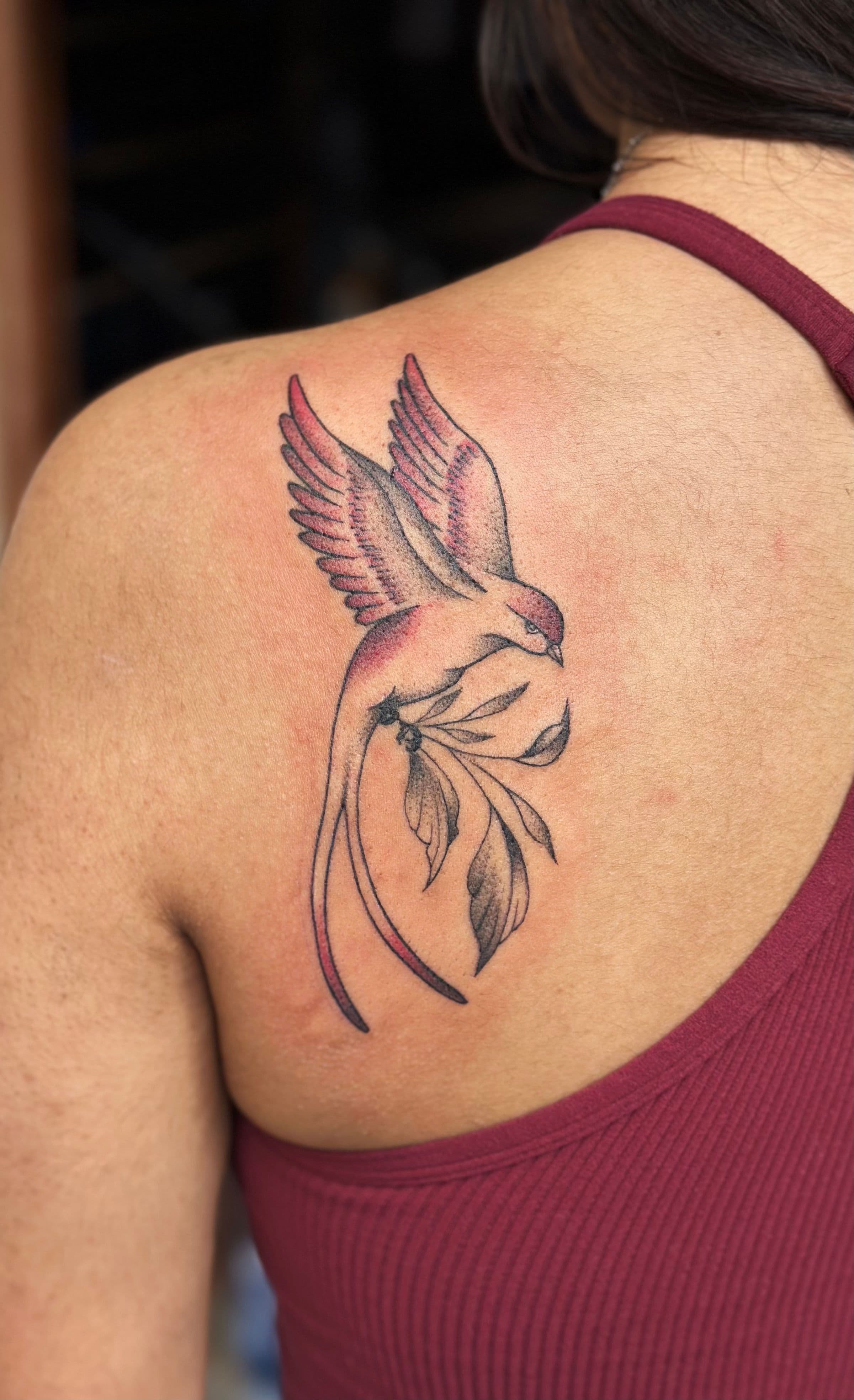Colorful bird tattoo with fine line work on upper back