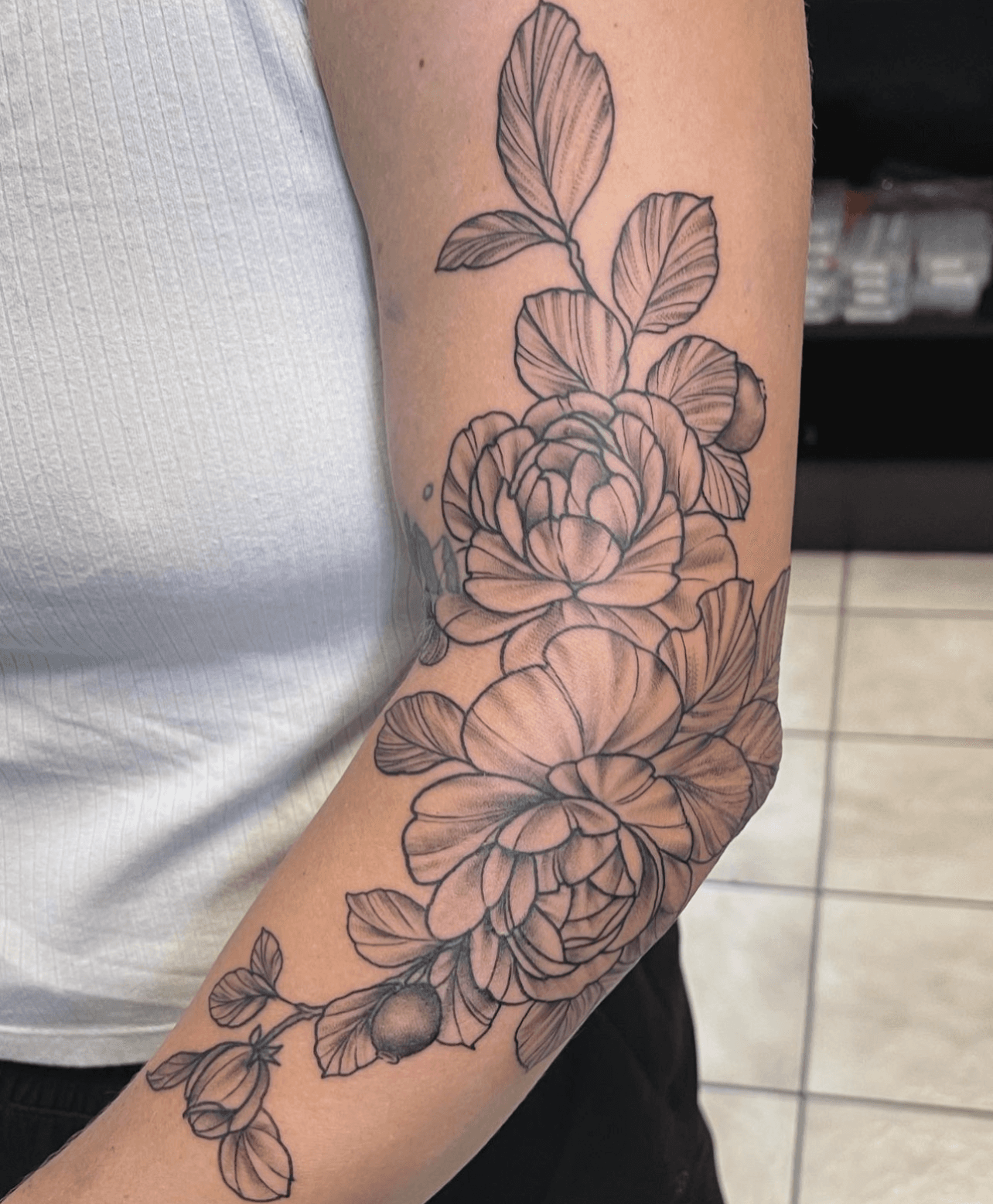 Black and grey floral tattoo on upper arm