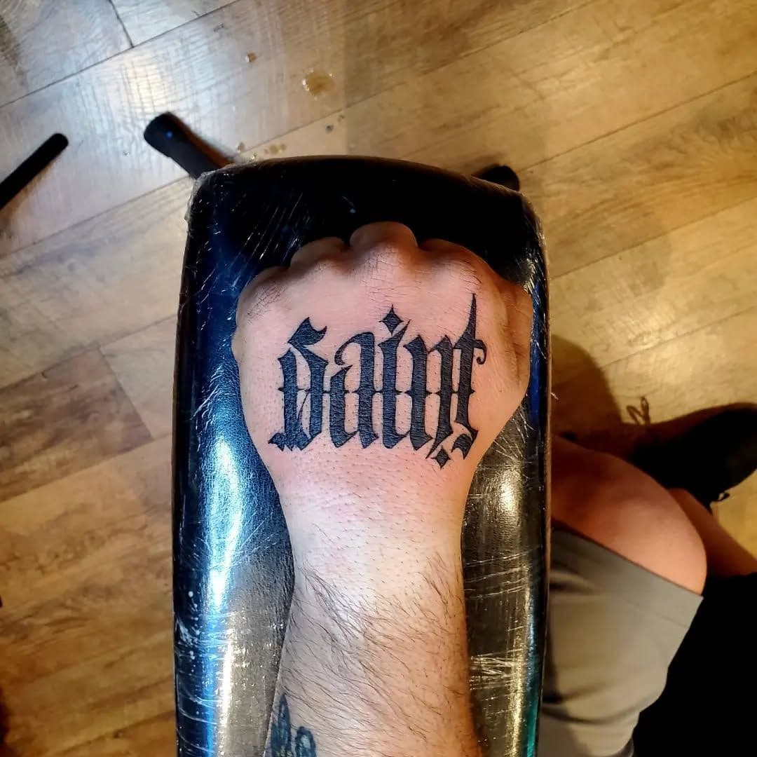 Black and grey Gothic lettering tattoo on hand