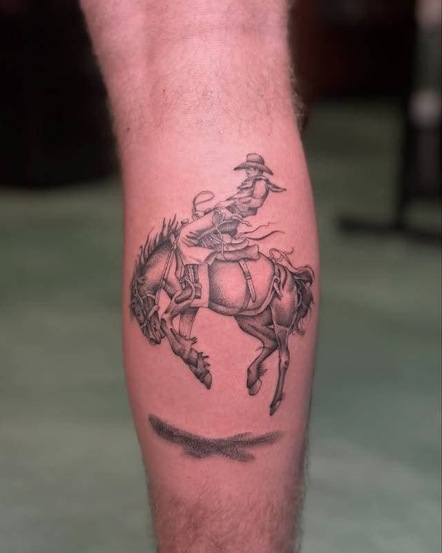 Black and grey realistic cowboy on horse tattoo on calf