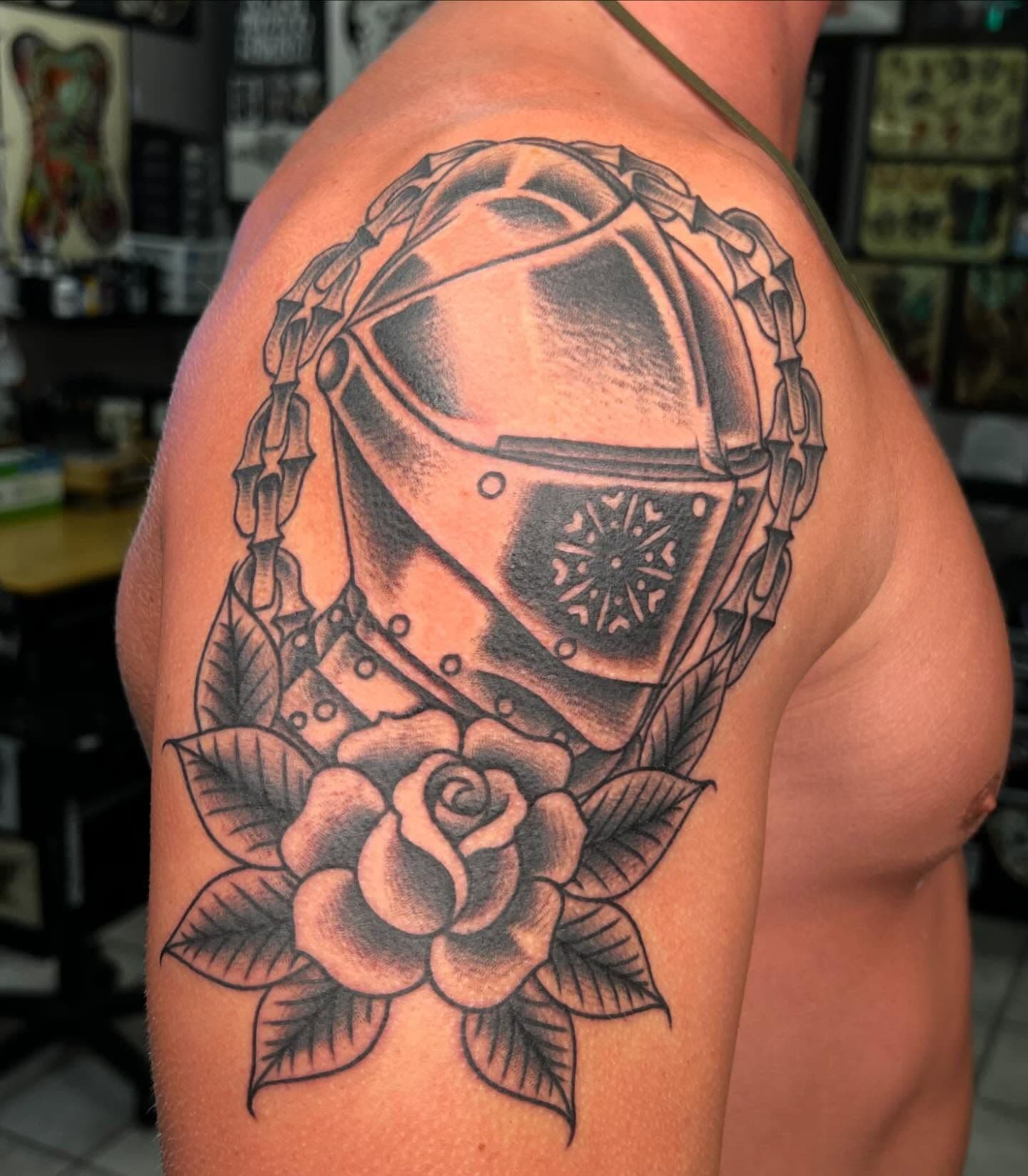 Black and grey knight helmet and rose tattoo on upper arm