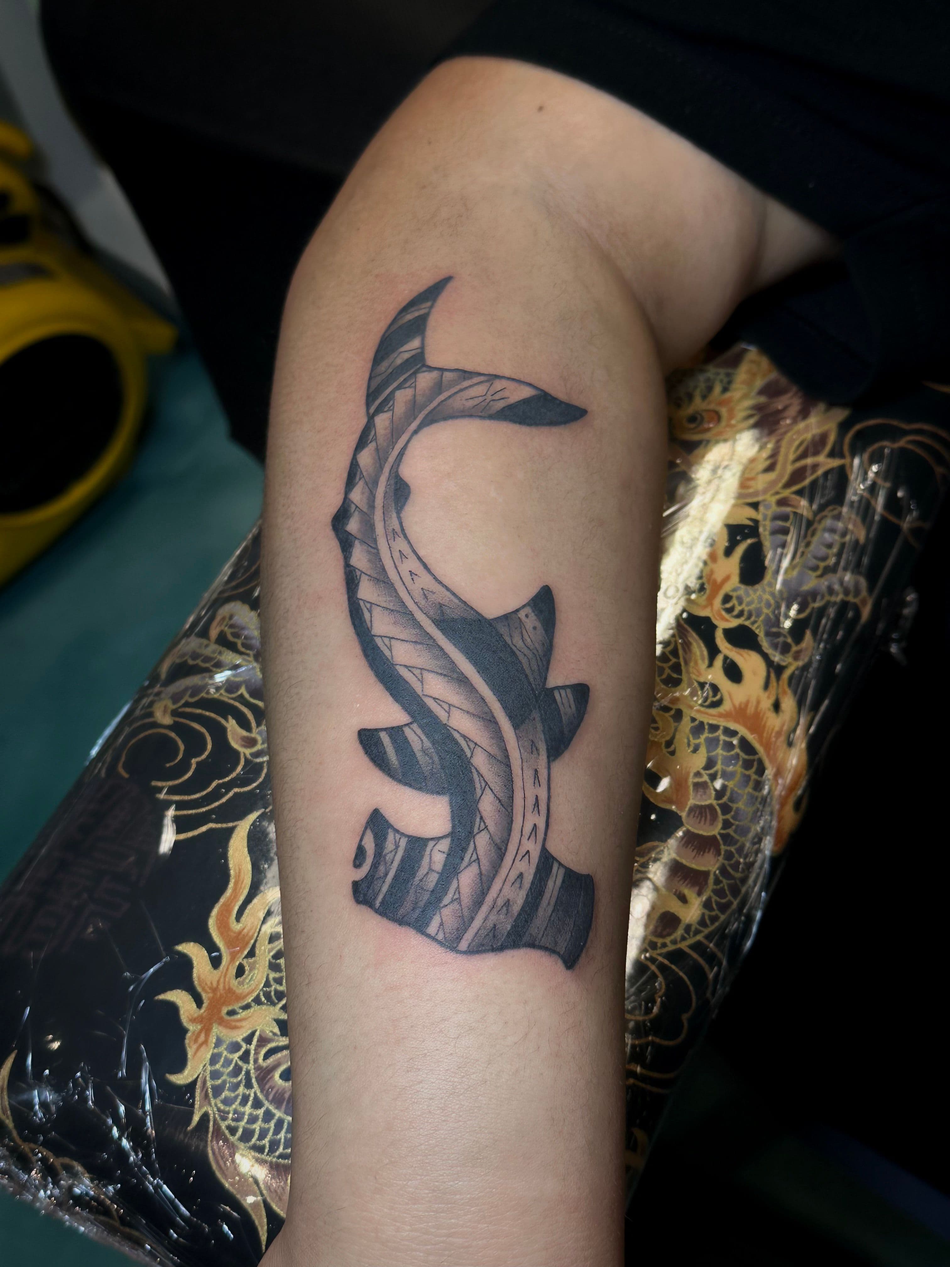 Black and grey tribal style tattoo on forearm